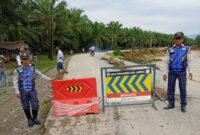 Petugas Dihub Langkat memasang rambu di sekitar jalan yang putus di Dusun Titi Kurus, Desa Karya Jadi, Kecamatan Batang Serangan.