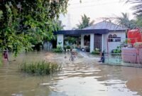 Anak-anak bermain air di halaman rumah warga yang kebanjiran.