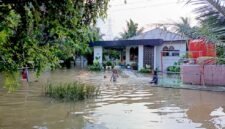 Anak-anak bermain air di halaman rumah warga yang kebanjiran.