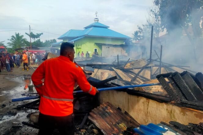 
Petugas Damkar memadamkan api yang membakar rumah semi permanen milik Nurlella.