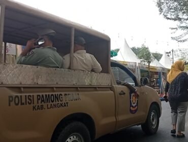 Petugas Satpol PP Langkat memberikan imbauan di areal pameran dengan mobil patroli.