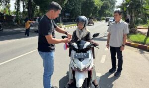 Aparat koplisian berpakain sipil membagikan bendera merah putih di depan Mapolres Langkat